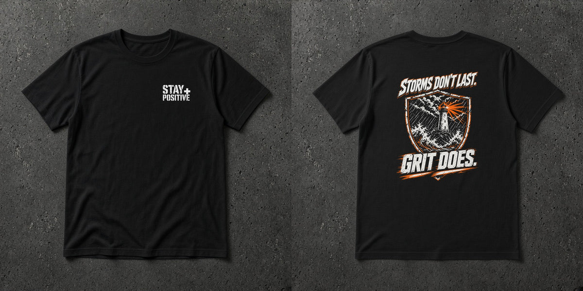 Black t-shirt with white Stay Positive chest logo and distressed white and safety orange lighthouse shield 'Storms Don't Last. Grit Does.' back print – Stay Positive by The Hillbillies, front and back view